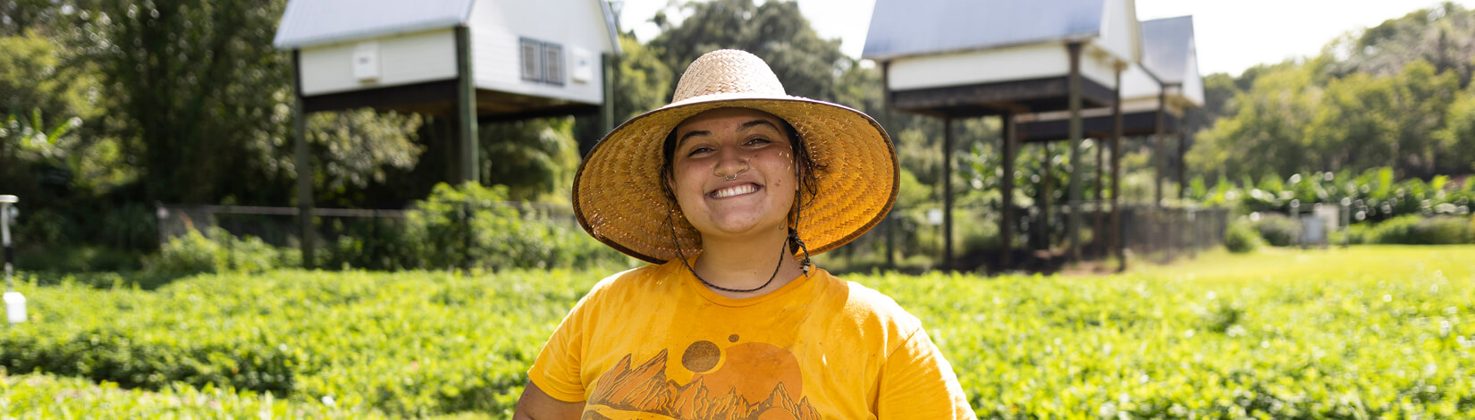 Woman standing in front of the Field and Fork Garden and bat houses